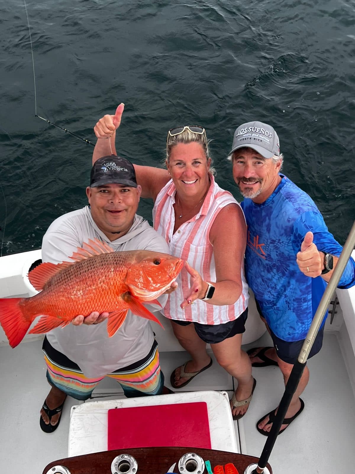 Three friends giving a thumbs-up with a red snapper