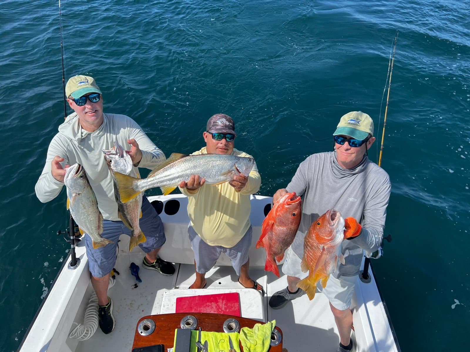 Three anglers holding the day's inshore catch aboard the Predator